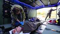 Blick in eine Patiententransporteinrichtung, links wird gerade ein Patient auf einer Trage behandelt