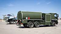 Tankwagen steht neben einem Kampfflugzeug.