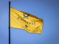 Eine gelbe Fahne mit der Aufschrift "Feldpost" weht vor blauem Himmel im Wind.