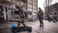  Soldiers in protective clothing and masks walk through tubs of liquid for decontamination.