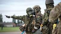 A German soldier wearing an NBC protective mask briefs a US soldier wearing an NBC protective mask on the situation. 