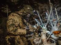  A soldier wearing protective gear examines something at a table with laboratory equipment.