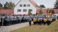 Ein großer Zug mit Musikern, Truppenfahnen und bewaffneten Soldaten auf einem Appellplatz
