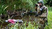  A soldier photographs a scene in which a doll representing a dead man lies in a trench