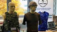 Military equipment is presented on two dummies, one wearing a protective vest and the other a T-shirt and helmet.