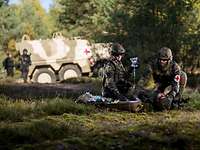 The Bundeswehr Medical Service Two paramedics care for a wounded man lying on the ground