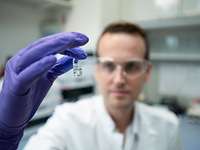 A person is sitting in a laboratory and looking at a vessel
