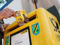  A hand puts a postcard into a mailbox