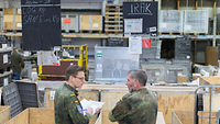  Two soldiers stand in front of crates containing packages.