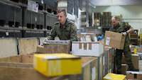  Two soldiers are sorting packages into containers for their respective areas of operation.