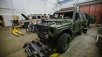 A man is working on a German army vehicle in a hall.