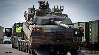  A battle tank is being loaded onto a heavy-duty transporter