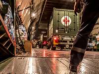 A truck with a red cross stands in the cargo hold of an airplane.