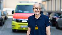 Porträt eines lächelnden Mannes, der vor einem Rettungswagen steht.
