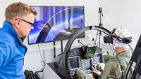 Ein Pilot sitzt im Simulator. Er trägt eine verkabelte Haube auf dem Kopf und eine VR-Brille.