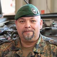 Ein Mann mit grünem Barret und einem silbernen Abzeichen schaut in die Kamera.