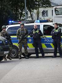 Zwei Polizisten und zwei Soldaten bewachen eine Straße