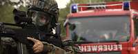Ein Soldat mit Gasmaske und Gewehr vor einem Feuerwehrauto