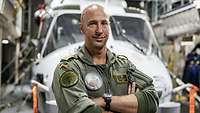 Ein Porträt von einem Soldaten. Im Hintergrund steht ein Hubschrauber.