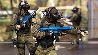 Soldaten mit VR-Brillen und Waffen bewegen sich in einem Raum