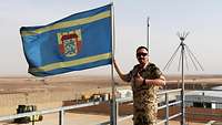 Ein Soldat steht vor einer Flagge 