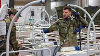 Zwei Soldaten, die Krankenpflegebetten aufbauen