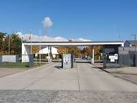 Betonierte zweispurige Einfahrt auf einen Kaserneneingang mit Zaun, Überdachung und Schaltergebäude