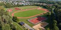 Blick von oben auf einen großen Sportplatz mit Tartanbahn, Ballspiel- und Fitnessflächen
