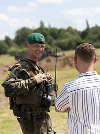 Tag der Bundeswehr 2025 in Neubrandenburg Ein Soldat steht mit einem Mann und einer Frau im Gelände und lächelt in die Kamera.