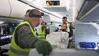 Soldaten schieben eine Patientin auf einer Bahre in einem Flugzeug an eine Behandlungsstation.