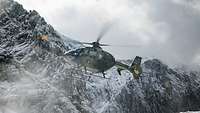 Aus der Froschperspektive ist ein Hubschrauber vor verschneiten Berggipfeln zu erkennen.