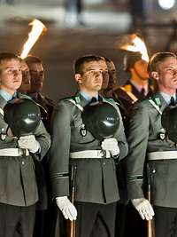 Angetretene Soldaten mit vor der Brust gehaltenem Helm in der Dämmerung vor Reichstagsgebäude