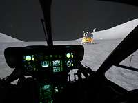 Aus einem dunklen Hubschraubercockpit ist die simulierte Mondlandschaft mit Raumkapsel zu sehen.