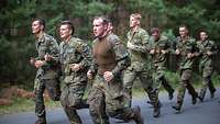 Mehrere Soldaten laufen auf einer asphaltierten Straße.