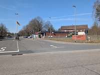 Blick auf vier Fahrspuren, die auf zwei Schlagbäume mit Wache und einer Flagge zuführen.