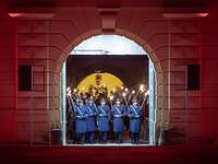 Eine Formation Soldaten marschiert mit Fackeln durch das Tor einer Festung.