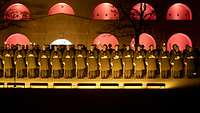 Soldaten in Formation stehen vor einer beleuchteten Festung bei Nacht.