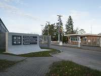 Stein mit dem Kasernenname daneben das Kasernentor und dahinter das Wachgebäude