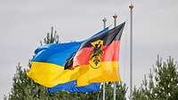 Eine russische und deutsche Flagge wehen nebeneinander im Wind. 