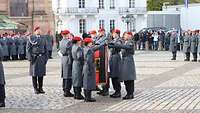 Soldatinnen und Soldaten stehen auf einem großen Platz, in der Mitte die Truppenfahne.
