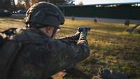 Ein Soldat hält mit beiden Händen eine Pistole fest und zielt auf eine Scheibe vor ihm.