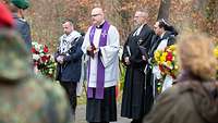 Vier Militärgeistliche stehen neben Blumenkränzen und feiern einen ökumenischen Gottesdienst 