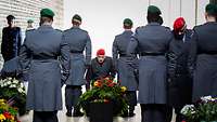 Generalinspekteur Carsten Breuer kniet vor einem Kranz im Ehrenmal der Bundeswehr.