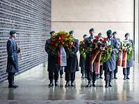 Soldaten tragen große Kränze in das Ehrenmal der Bundeswehr. Ein Soldat mit Trompete steht daneben.
