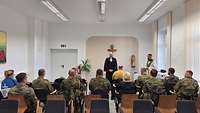 Ein Pfarrer steht vor Soldaten und hält eine Andacht.