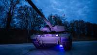 Ein Panzer im blauen Licht steht bei Dunkelheit auf einer asphaltierten Fläche.