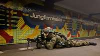 Ein Soldat liegend mit Gewehr im Anschlag auf einem U-Bahn Steig