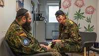 Eine Soldatin und ein Militärrabbiner sitzen sich gegenüber und sprechen miteinander.