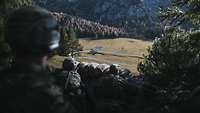 Im Wald am Berghang liegen Soldaten mit Gewehren in Stellung und schauen ins Tal.