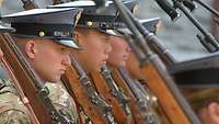 Mehrere Kadetten stehen mit Waffen nebeneinander während der Formalausbildung.
